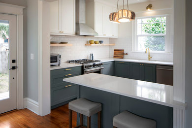 Mid-sized arts and crafts u-shaped light wood floor kitchen photo in Portland with an undermount sink, raised-panel cabinets, blue cabinets, quartz countertops, white backsplash, ceramic backsplash, stainless steel appliances, an island and white countertops