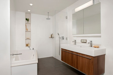 Bathroom - mid-sized modern master ceramic tile and gray floor bathroom idea in Boston with flat-panel cabinets, medium tone wood cabinets, a two-piece toilet, white walls, a wall-mount sink and solid surface countertops