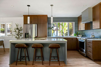 Kitchen - 1950s l-shaped medium tone wood floor kitchen idea in Portland with an undermount sink, flat-panel cabinets, dark wood cabinets, blue backsplash, ceramic backsplash, stainless steel appliances, an island and white countertops