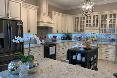 Example of a large classic l-shaped kitchen design in Jacksonville with a double-bowl sink, raised-panel cabinets, beige cabinets, granite countertops, mosaic tile backsplash, black appliances, an island and gray countertops