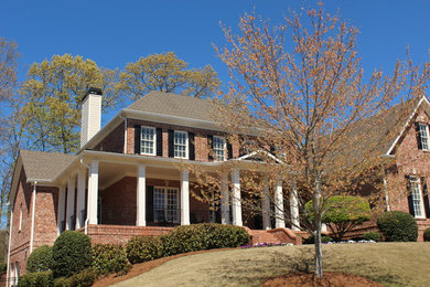 Large elegant red two-story brick house exterior photo in Atlanta with a hip roof and a shingle roof