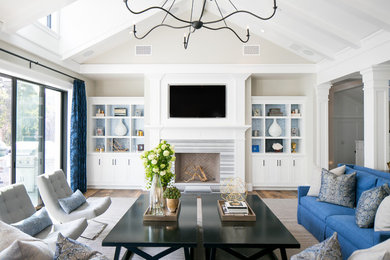 Photo of a transitional family room in Orange County with beige walls, a standard fireplace and a wall-mounted tv.