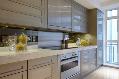 Inspiration for a medium sized contemporary galley kitchen in London with a double-bowl sink, recessed-panel cabinets, green cabinets, marble worktops, stainless steel appliances, marble flooring, white worktops, metallic splashback and mirror splashback.