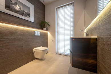 Design ideas for a medium sized contemporary cloakroom in London with a wall mounted toilet, grey tiles, ceramic tiles, a wall-mounted sink, feature lighting and a floating vanity unit.
