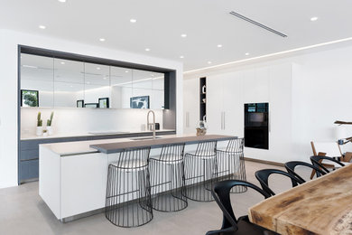 Example of a mid-sized trendy l-shaped kitchen design in Chicago with flat-panel cabinets, white cabinets, an island and white countertops