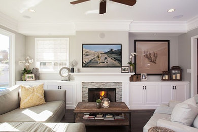 Example of a large trendy open concept dark wood floor living room design in Los Angeles with beige walls, a standard fireplace, a wood fireplace surround and a wall-mounted tv
