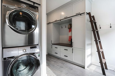 Utility room - large porcelain tile utility room idea in Other with shaker cabinets, a stacked washer/dryer and white cabinets