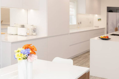 Imagen de cocina comedor moderna pequeña con fregadero de un seno, armarios con paneles lisos, salpicadero blanco, electrodomésticos blancos, suelo gris y encimeras blancas