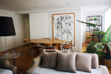 Ejemplo de comedor contemporáneo de tamaño medio abierto con paredes blancas, suelo de madera en tonos medios y cuadros