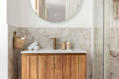 This is an example of a medium sized mediterranean ensuite bathroom in London with freestanding cabinets, light wood cabinets, a built-in shower, a wall mounted toilet, beige tiles, porcelain tiles, beige walls, porcelain flooring, a built-in sink, beige floors, a sliding door, white worktops, a wall niche, a single sink and a freestanding vanity unit.