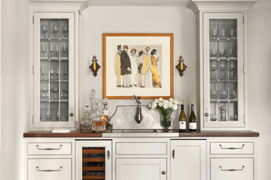 Wet bar - mid-sized traditional galley dark wood floor and brown floor wet bar idea in St Louis with flat-panel cabinets, white cabinets, wood countertops, white backsplash, brown countertops and marble backsplash