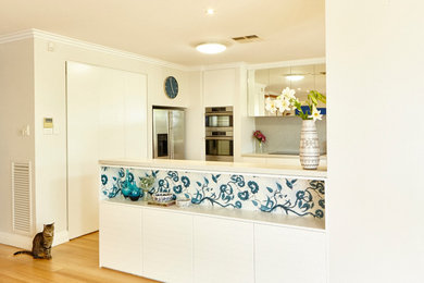 This is an example of a mid-sized contemporary u-shaped eat-in kitchen in Perth with a drop-in sink, beaded inset cabinets, white cabinets, quartz benchtops, grey splashback, mosaic tile splashback, stainless steel appliances, medium hardwood floors and no island.