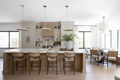 Example of a transitional galley light wood floor and beige floor eat-in kitchen design in Phoenix with an undermount sink, shaker cabinets, beige cabinets, beige backsplash, stone slab backsplash, paneled appliances, an island and white countertops