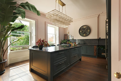 Design ideas for a medium sized traditional l-shaped kitchen in Other with shaker cabinets, green cabinets, quartz worktops, black splashback, black appliances, an island and black worktops.