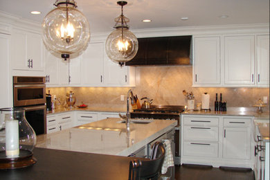 Example of a large transitional u-shaped dark wood floor enclosed kitchen design in New York with a farmhouse sink, beaded inset cabinets, white cabinets, limestone countertops, beige backsplash, stone slab backsplash, stainless steel appliances and an island