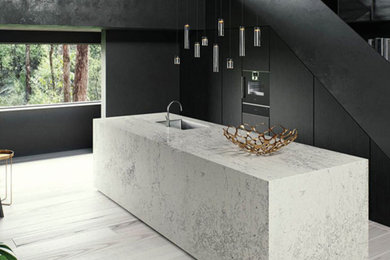 Inspiration for a modern kitchen remodel in Los Angeles with an undermount sink, flat-panel cabinets, black cabinets, marble countertops, paneled appliances, an island and white countertops