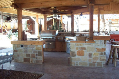 Imagen de patio rústico grande en patio trasero con cocina exterior, losas de hormigón y pérgola