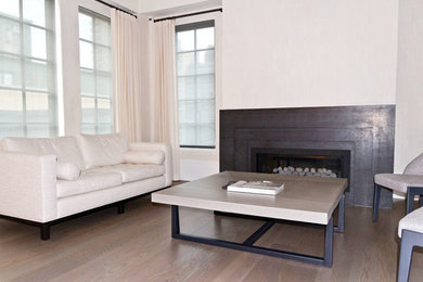 Photo of a mid-sized contemporary living room in New York with white walls, medium hardwood floors, a standard fireplace, a metal fireplace surround and brown floor.