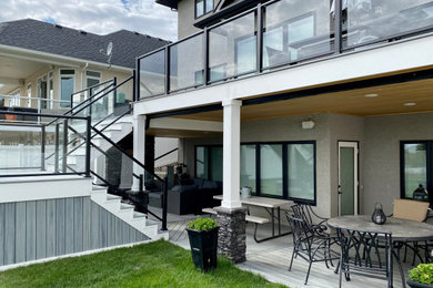 Large minimalist backyard second story glass railing deck photo in Other with a fireplace and a roof extension
