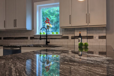 Example of a large trendy u-shaped porcelain tile and gray floor kitchen design in Ottawa with an undermount sink, shaker cabinets, gray cabinets, granite countertops, gray backsplash, subway tile backsplash, stainless steel appliances, a peninsula and black countertops