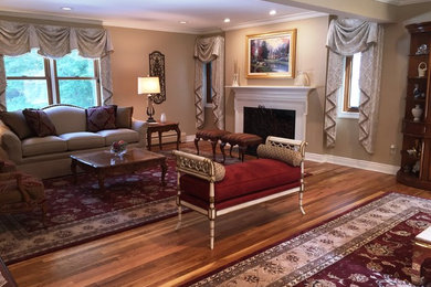 This is an example of a large traditional formal enclosed living room in New York with beige walls, a standard fireplace, a stone fireplace surround, a freestanding tv, medium hardwood floors and brown floor.