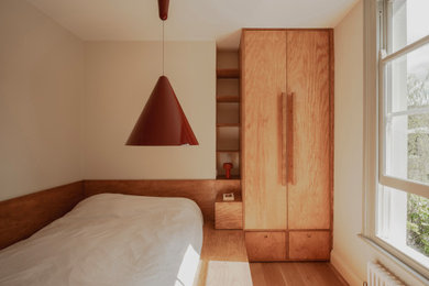 Small modern master bedroom in London with medium hardwood flooring and feature lighting.