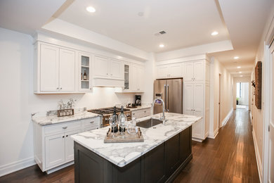 Photo of a mid-sized transitional l-shaped eat-in kitchen in DC Metro with an undermount sink, shaker cabinets, white cabinets, marble benchtops, white splashback, stainless steel appliances, medium hardwood floors and with island.