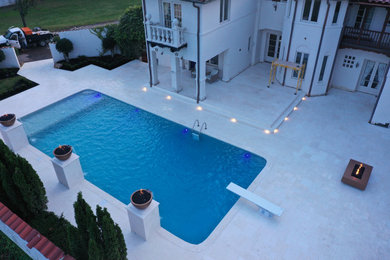 Diseño de piscina elevada mediterránea grande rectangular en patio trasero con paisajismo de piscina y adoquines de piedra natural