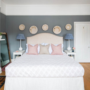 Klassisches Hauptschlafzimmer mit grauer Wandfarbe, hellem Holzboden, Kaminofen und gefliester Kaminumrandung in London