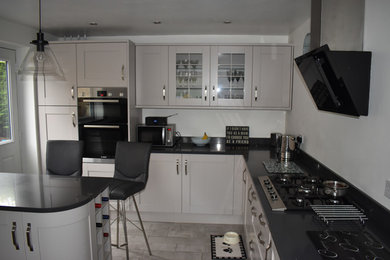 Foto di una cucina a L minimal di medie dimensioni con ante in stile shaker, top in quarzite e penisola