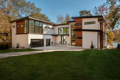 Photo of a large modern two-storey white house exterior in Charlotte with stone veneer, a shed roof, a metal roof and a black roof.