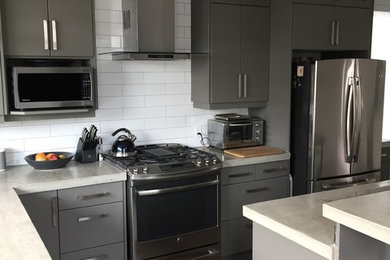 Eat-in kitchen - modern l-shaped medium tone wood floor eat-in kitchen idea in Edmonton with an undermount sink, flat-panel cabinets, gray cabinets, concrete countertops, white backsplash, ceramic backsplash and stainless steel appliances