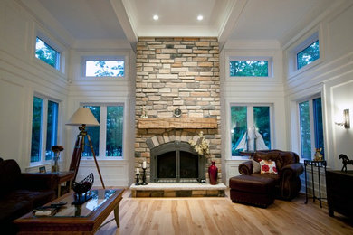 Large elegant open concept medium tone wood floor and multicolored floor family room photo in Ottawa with white walls, a standard fireplace, a stone fireplace and a wall-mounted tv