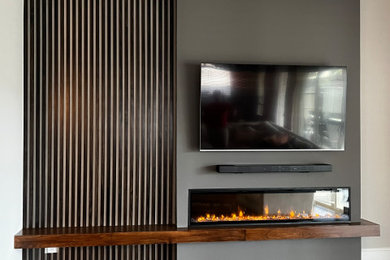 Example of a mid-sized minimalist enclosed ceramic tile and brown floor living room library design in Houston with gray walls, a standard fireplace, a wood fireplace surround and a wall-mounted tv