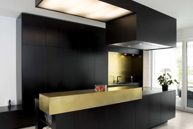 Design ideas for a contemporary kitchen in Other with black cabinets, solid surface benchtops, metallic splashback, metal splashback, black appliances, with island, beige floor and black benchtop.