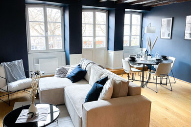 Foto de sala de estar abierta clásica renovada de tamaño medio sin chimenea con paredes azules, suelo de madera clara, televisor independiente, suelo amarillo y vigas vistas
