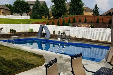 This is an example of a mid-sized modern backyard rectangular pool in Omaha with concrete slab and a water slide.