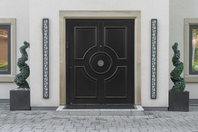 Cette photo montre une porte d'entrée moderne avec un mur blanc, une porte double et une porte noire.