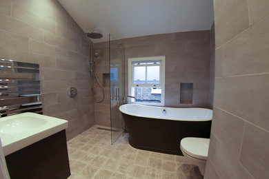 This is an example of a medium sized modern family bathroom in London with a freestanding bath, a walk-in shower, a wall mounted toilet, porcelain tiles and a wall-mounted sink.