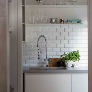 Moderne Küche in L-Form mit Vorratsschrank, braunem Holzboden, weißen Schränken, Laminat-Arbeitsplatte, Küchenrückwand in Weiß, Rückwand aus Zementfliesen und grauer Arbeitsplatte in Auckland