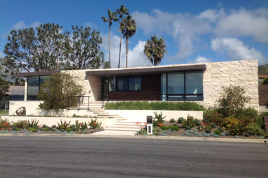 Photo of a mid-sized contemporary one-storey beige house exterior in Orange County with stone veneer and a flat roof.