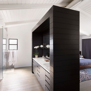 Exemple d'une salle de bain principale rétro avec un lavabo encastré, un placard à porte plane, des portes de placard noires, une baignoire indépendante, une douche à l'italienne, un carrelage gris, un mur blanc et un sol en bois clair.