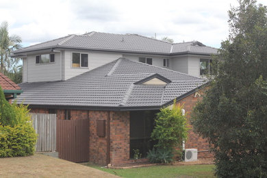Photo of a large modern two-storey multi-coloured house exterior in Brisbane with mixed siding, a hip roof and a tile roof.
