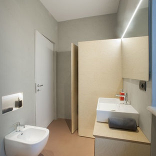 Ispirazione per un bagno di servizio moderno con ante a filo, ante in legno chiaro, WC sospeso, piastrelle grigie, pareti grigie, pavimento in cemento, lavabo integrato, top in legno, pavimento rosso e top beige