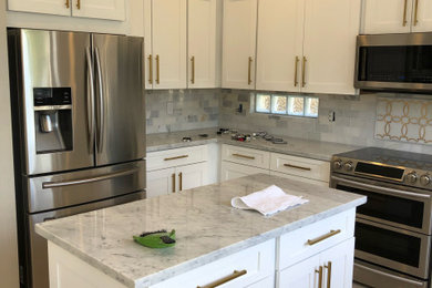 Example of a large classic u-shaped ceramic tile and beige floor kitchen design in Cincinnati with a farmhouse sink, shaker cabinets, white cabinets, marble countertops, marble backsplash, stainless steel appliances, two islands and multicolored countertops