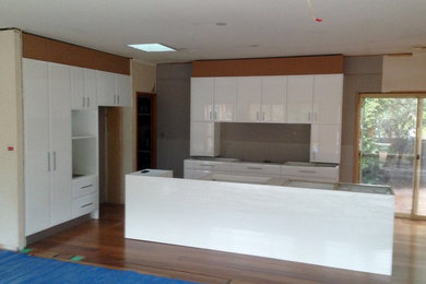 Kitchen in Canberra - Queanbeyan with white cabinets, solid surface benchtops and glass sheet splashback.