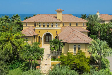 Example of a huge island style yellow exterior home design in Other