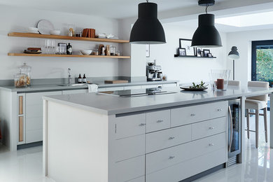 Photo of a contemporary galley kitchen in Belfast with a submerged sink, flat-panel cabinets, white cabinets, an island, grey floors and grey worktops.