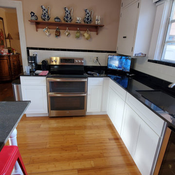 Contemporary Kitchen Remodel With White Cabinets and Black Countertop
