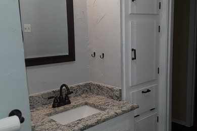 Small minimalist bathroom photo in Dallas with white cabinets, white walls, an undermount sink, granite countertops and beige countertops